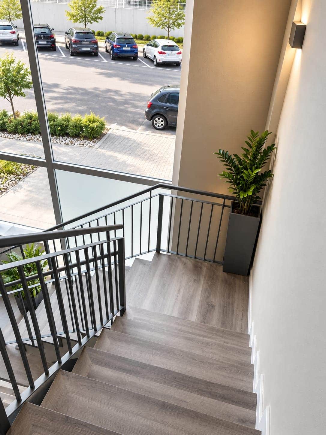 Escalera vista desde el rellano superior con barandilla metálica y ventanal