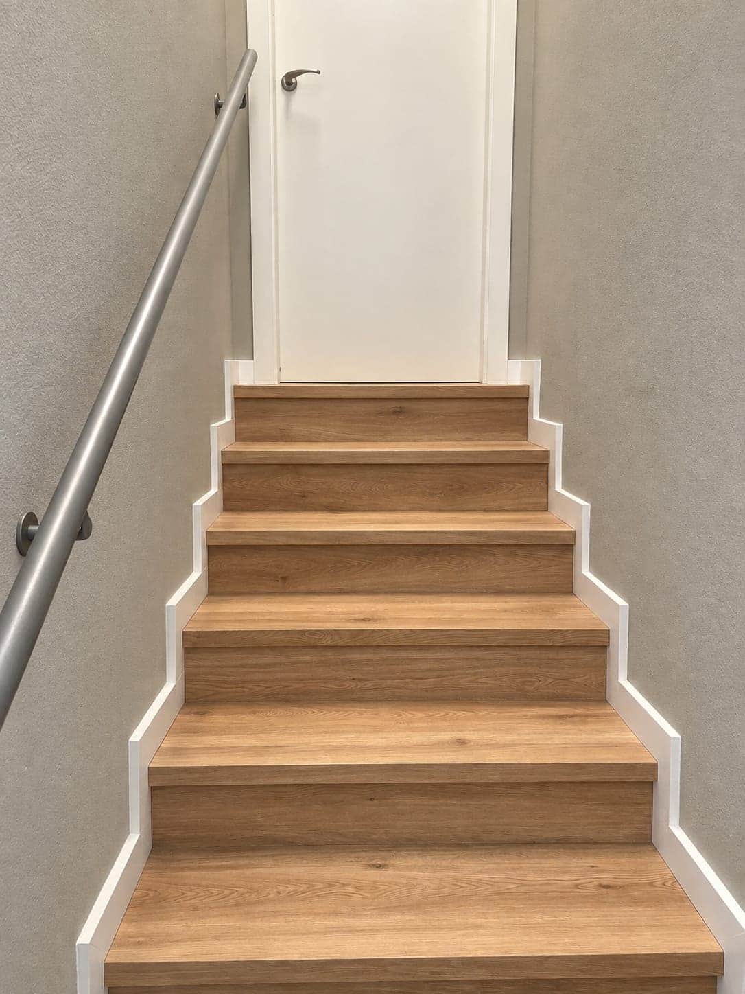 Tramo recto de escalera con huellas y contrahuellas forradas en madera clara