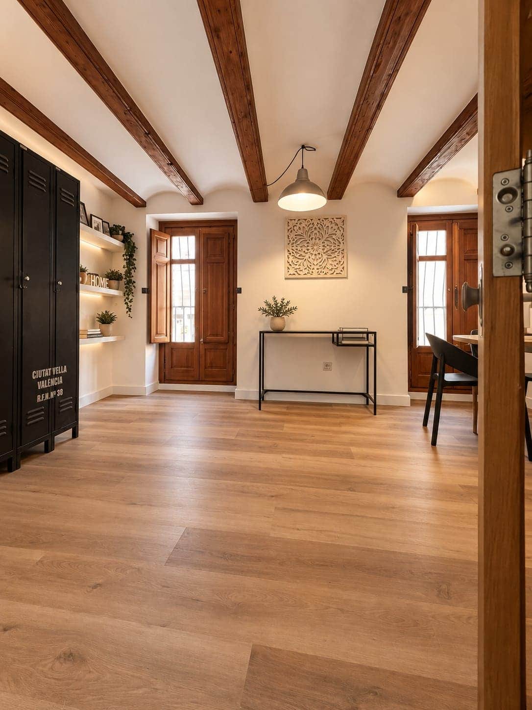 Entrada con puertas de madera originales, armario negro y suelo de lama clara